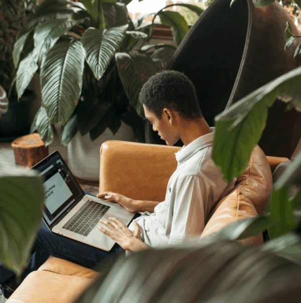 Worker on a laptop while seated in a lounge area with plants